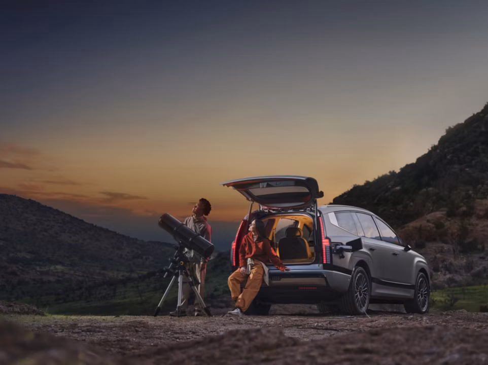Parked IONIQ 9 with tailgate open using V2L for telescope for stargazing.